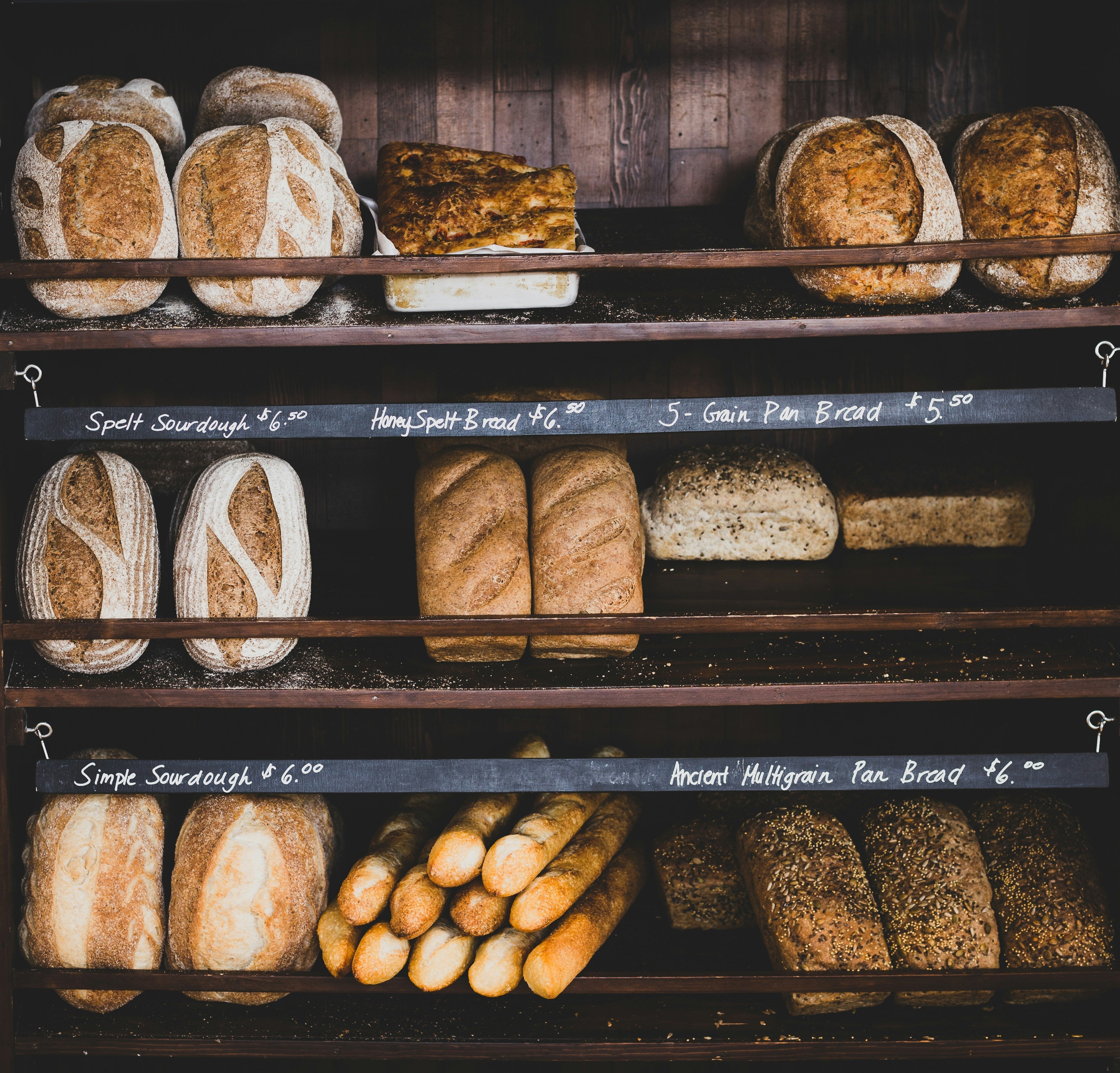 A variety of loaves of bread on shelves at a bakery